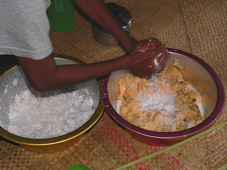 The other main ingredient is coconut milk. It is obtained by grating the inside of the coconut seed to extract the white fleshy part (the meat) and mixing it with the coconut water. The milk is extracted by squeezing a handful of the mixture over the banana paste.